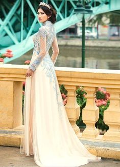 a woman in a wedding dress standing on a bridge looking back at the camera and wearing a tiara