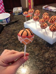 a hand is holding a lollipop with basketballs on it in front of other lollipops