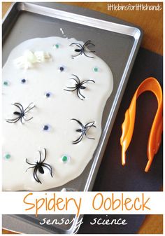 a tray with spider oobleck on it next to an orange handled utensil