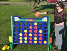 a woman standing in front of a giant connect - a - row game on the grass