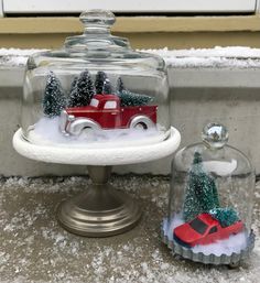 a red truck under a glass dome with snow on the ground and trees in it