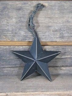 a black metal star hanging on a wooden wall next to a gray rope and wood planks