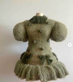 a teddy bear dressed in a dress with buttons on it's collar and sleeves