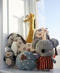 several stuffed animals sitting on top of a window sill