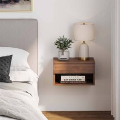 a bed with white sheets and pillows next to a night stand on a wooden floor