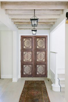 a large wooden door sitting inside of a hallway next to a stair case and light fixture