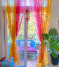 a living room filled with furniture and a window covered in yellow drapes next to a potted plant