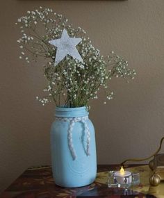 a blue mason jar with baby's breath flowers in it and a lit candle