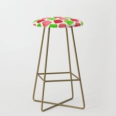 an upholstered stool with red and green apples on the seat, against a white background