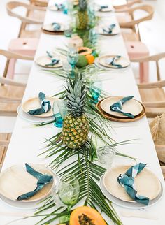 a long table with pineapples and plates on it