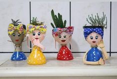 three small ceramic pots with plants in them on a shelf next to a tile wall