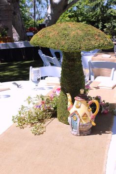 the table is set with an umbrella shaped planter and teapot on top of it