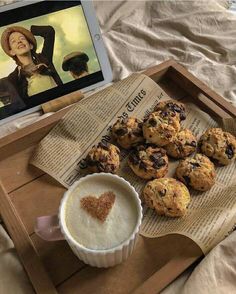 a tray with muffins and a cup of coffee next to an ipad on a bed