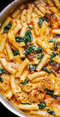 a pan filled with pasta and spinach covered in sauce