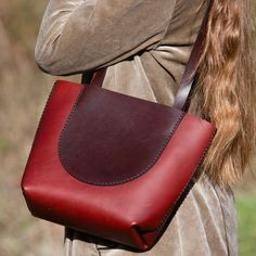 a woman carrying a red and brown leather handbag on her shoulder with long hair