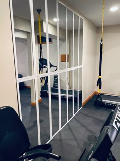 a gym with exercise equipment and mirrors in the wall, including an exercise bike hanging from a rope