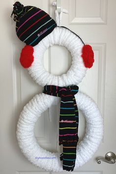 a crocheted snowman wreath hanging on the front door with a hat and scarf