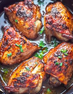 some meat is cooking in a pan with sauce and herbs on the side, ready to be eaten