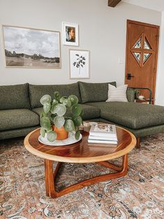 a living room with green couches and pictures on the wall above it, along with a wooden coffee table