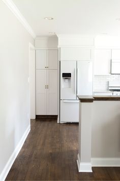 an empty kitchen with white cabinets and wood floors