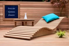 a wooden chaise lounge chair sitting on top of a hard wood floor next to a table