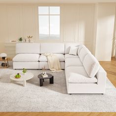 a living room with white furniture and wood flooring, including a large sectional couch