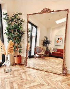 a large mirror sitting on top of a wooden floor next to a potted plant