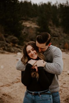 a man and woman hugging each other on the beach