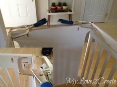 a baby gate is being installed in a room with white walls and wooden floors,