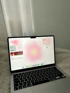 an open laptop computer sitting on top of a white rug next to a window with curtains