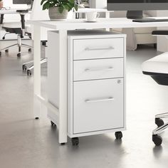 a white desk with two drawers and a potted plant