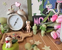 small figurines are sitting on a table next to an alarm clock and flowers