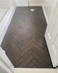 a bathroom with white walls and wood flooring in the shower area is shown from the doorway