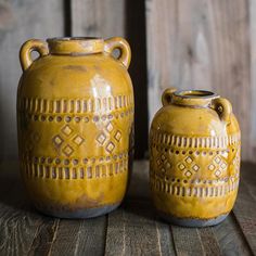 two yellow vases sitting on top of a wooden table