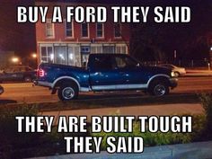 a blue truck parked in front of a red brick building with the words, buy a ford they said they are built tough they said