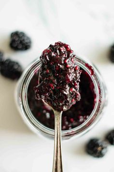 a spoon full of blueberry sauce with berries around it