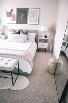 a white bed sitting in a bedroom next to two pictures on the wall above it