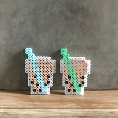 two small pixel art pieces sitting on top of a wooden table next to each other