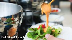 a person pouring dressing onto a salad in a bowl