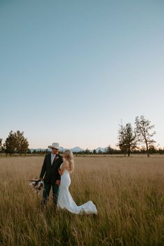 a bride and groom walking through tall grass