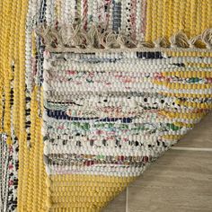 an area rug with yellow and white colors on the floor next to a tile floor