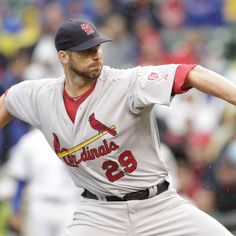 a baseball player pitching a ball on top of a field in front of a crowd