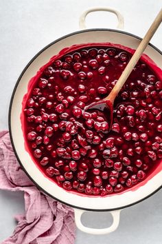 cranberry sauce in a pot with a wooden spoon and pink napkin on the side