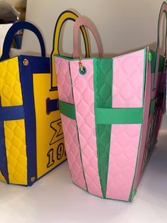 two colorful bags sitting next to each other on top of a white table with blue and yellow handles