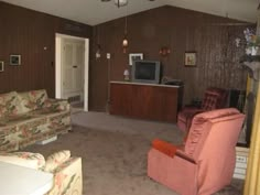 a living room filled with furniture and a flat screen tv on top of a wooden wall