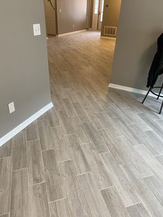 an empty living room with hard wood flooring and gray walls, along with a black chair