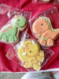 three decorated cookies sitting on top of plastic bags next to another cookie in the shape of dinosaurs