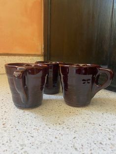 three brown coffee mugs sitting on top of a counter