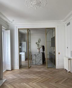 a woman is standing in an empty room with mirrors on the wall and doors open