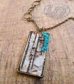 a necklace with blue beads on it sitting on a piece of wood next to a chain